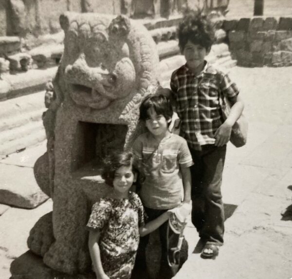A young Dr. Bermudez stands with her two brothers in front of a statue in India in 1975