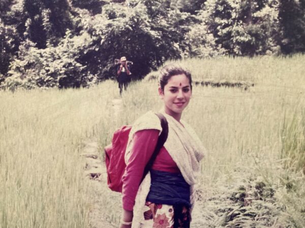 Dr. Bermudez stands in a field in traditional Nepali dress in 1987