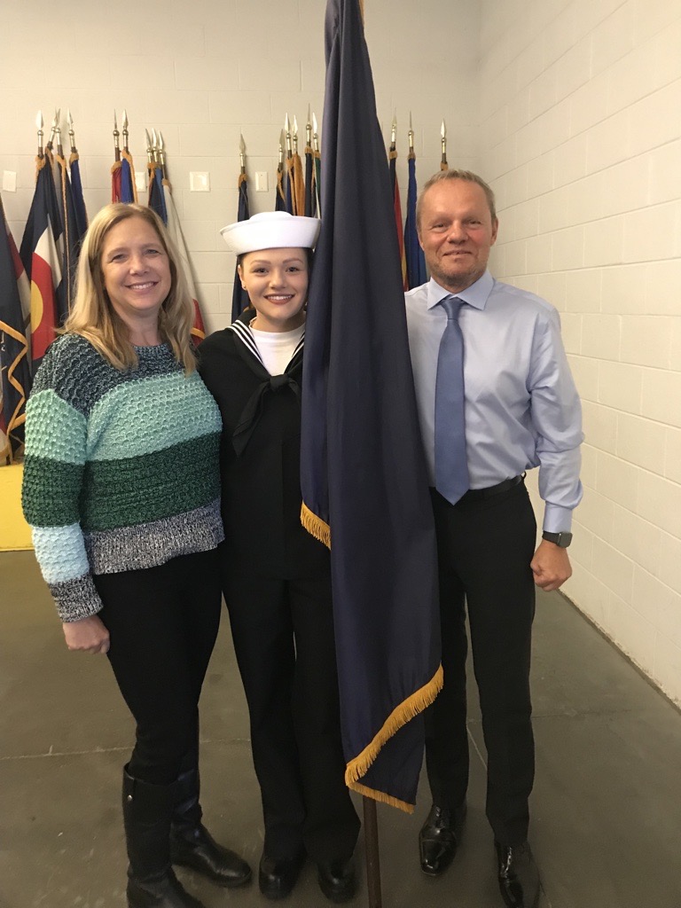 Gary stands with his wife and daughter next to a flag