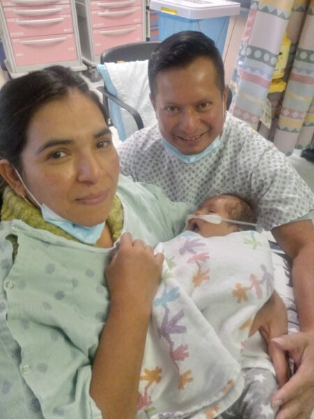 A mother and father hold their newborn son who is in the hospital.